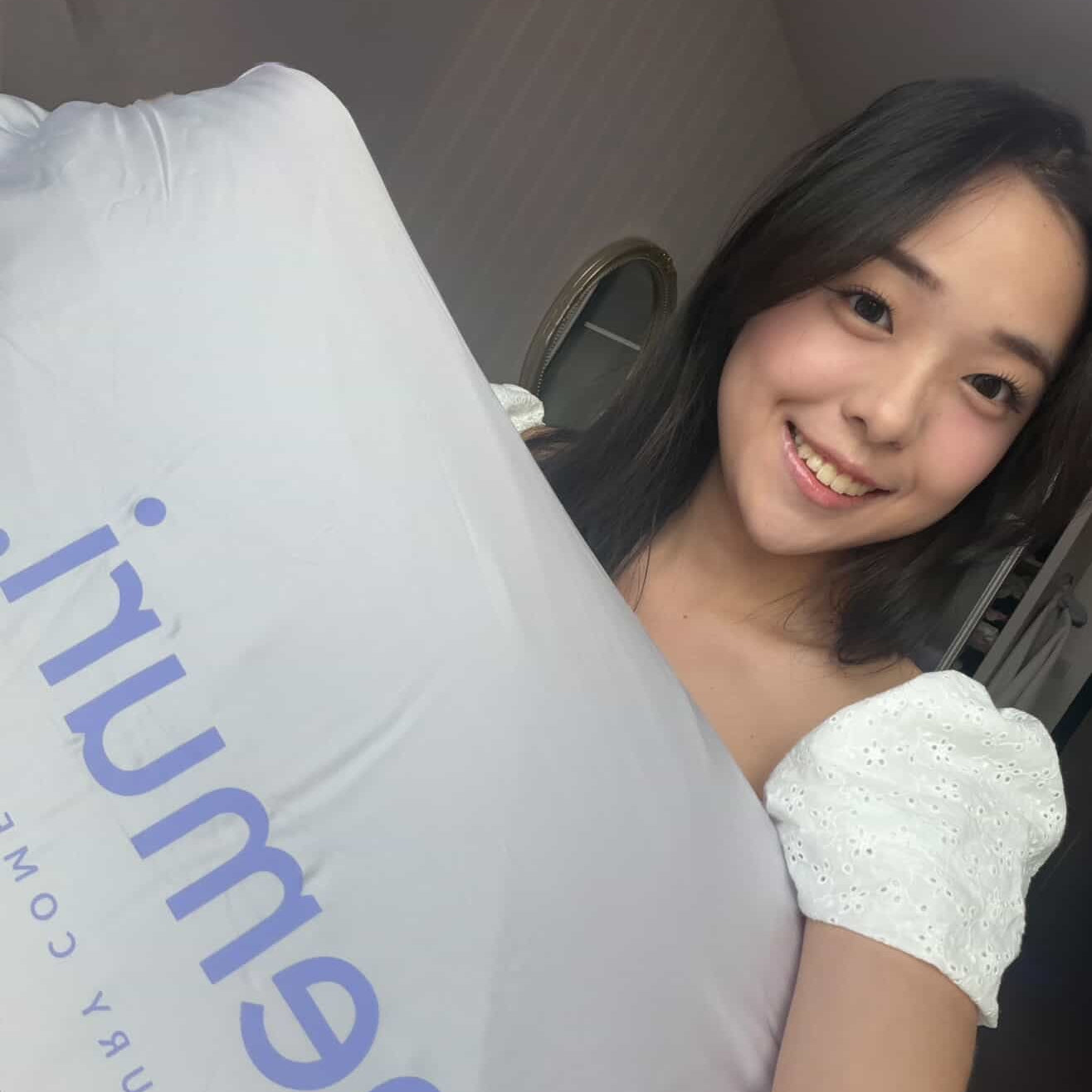 Person holding a large white pillow with 'nemuri' branding