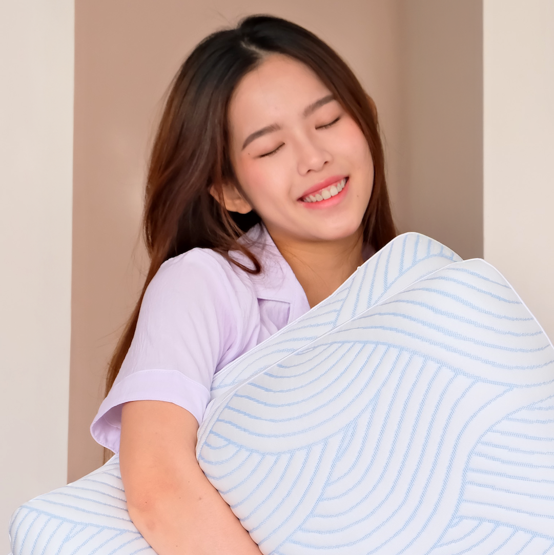 Woman holding a large light blue Nemuri pillow against a neutral background