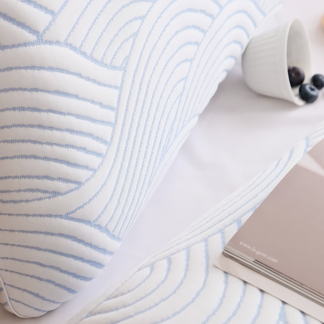 Close-up of a textured fabric with blue lines on a white Nemuri Pillow, featuring a notebook and berries.